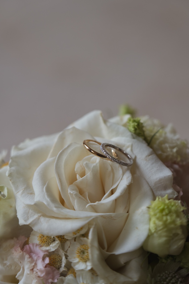 Photographie des alliance des mariés dans les fleurs